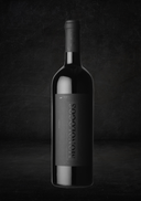 Schwarz etikettierte Weinflasche mit mattem Finish, dramatisch inszeniert vor dunklem, struktur­iertem Hintergrund.
